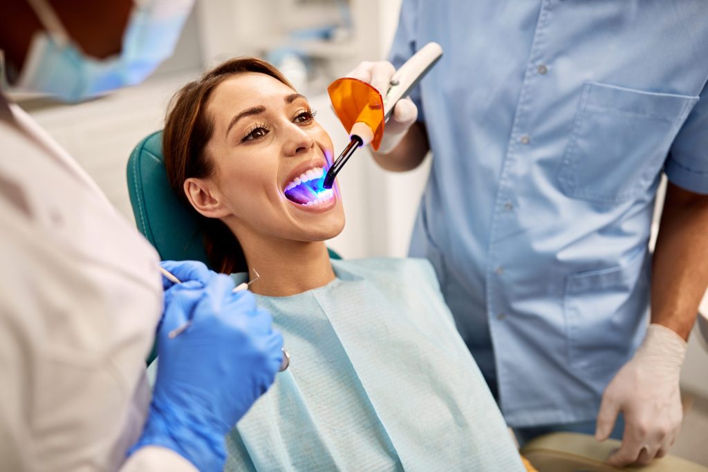Dentist curing a sealant with a blue light